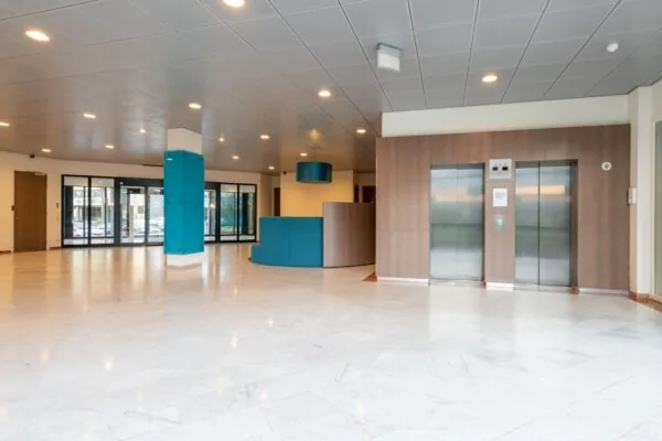 Moderne entreehal aan de De Bruyn Kopsstraat met marmeren vloer, liften en balie.